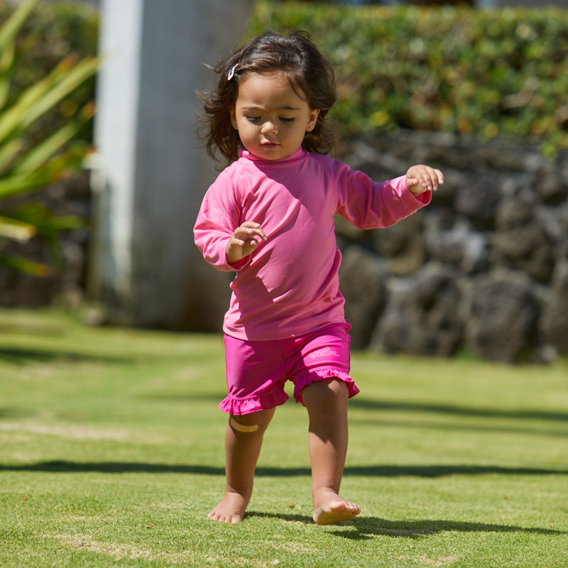 Little girl playing in UV Skinz's baby long sleeve swim shirt in hot pink|hot-pink