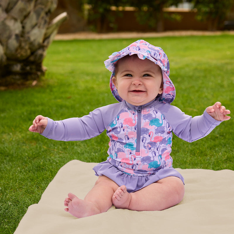 baby girl sitting in grass in swim flap hat|fancy-flamingos