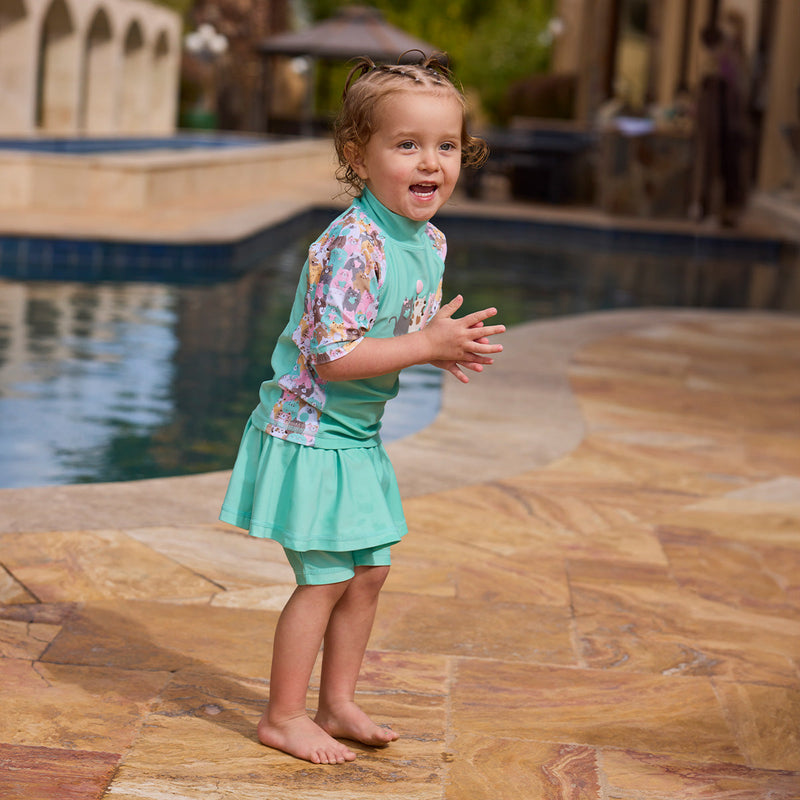 girl clapping by pool in skirted swim jammerz in seaglass