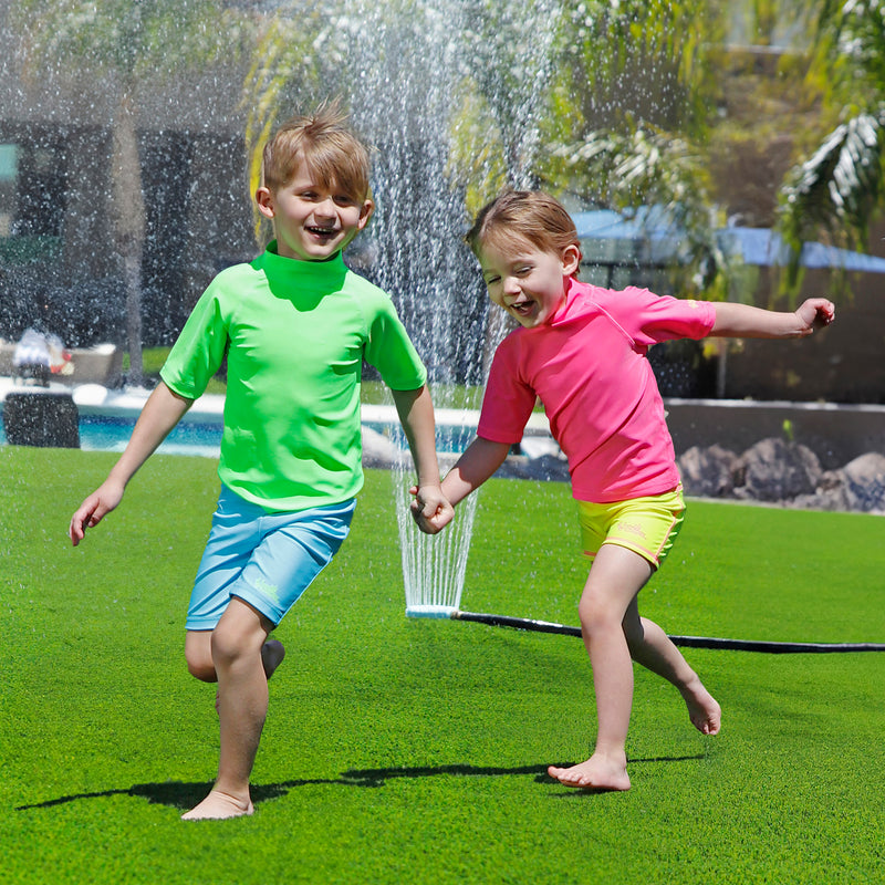 kids having fun in the sprinklers wearing kids neon magic print sun and swim shirt|neon-pups