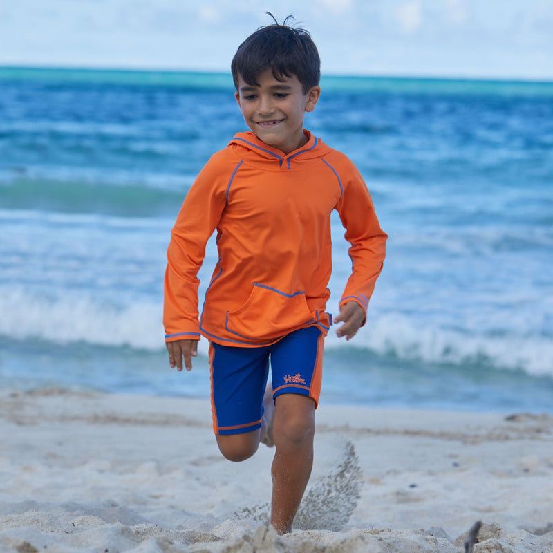 Little boy in UV Skinz's boy's swim shorts in navy orange|navy-orange