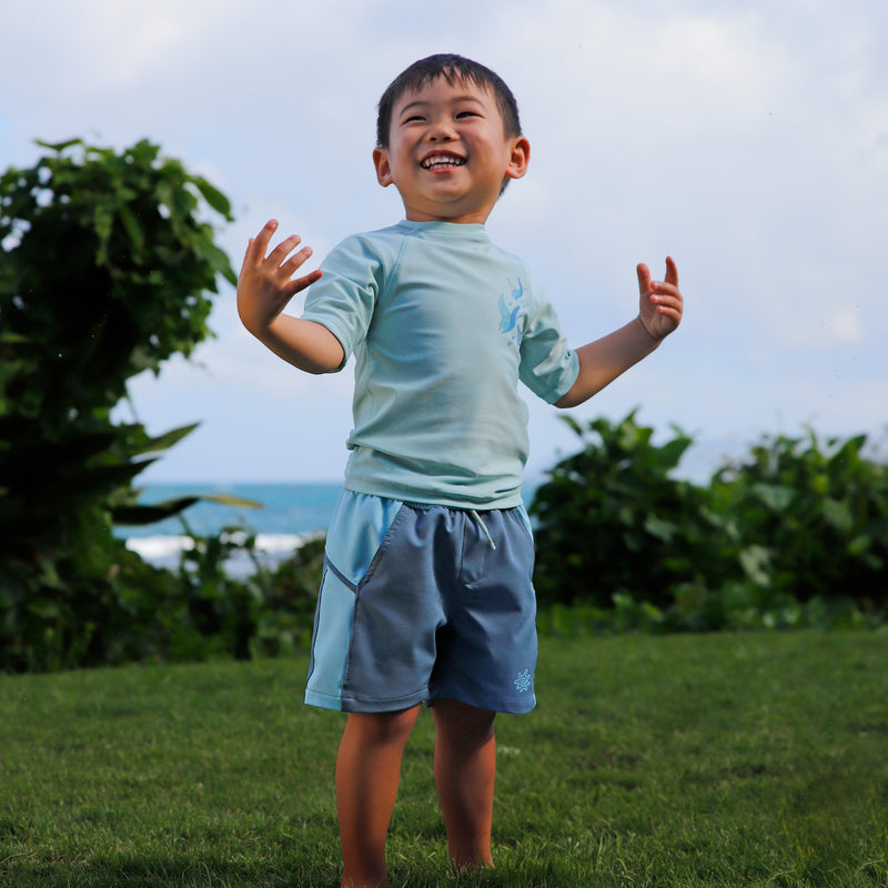 boy in grass in kids crew sunny swim shirt in gliding rays|gliding-rays