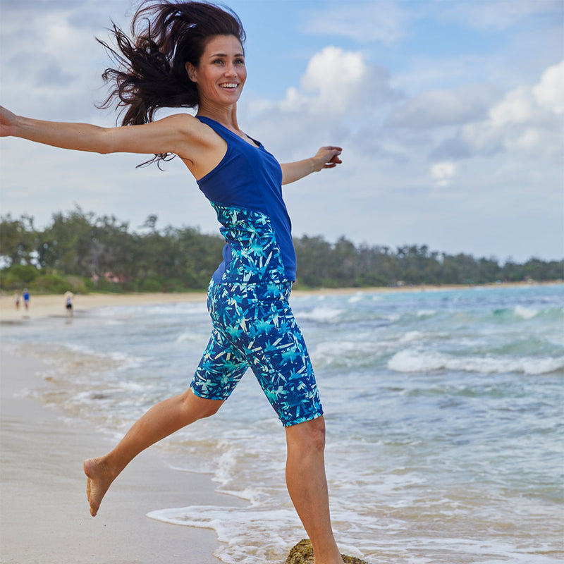 Woman jumping into the ocean in UV Skinz's women's swim tank|sage