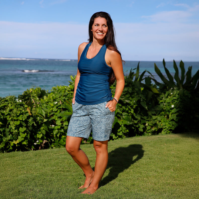 woman posing by the ocean in women's board shorts in imprinted shells|imprinted-shells