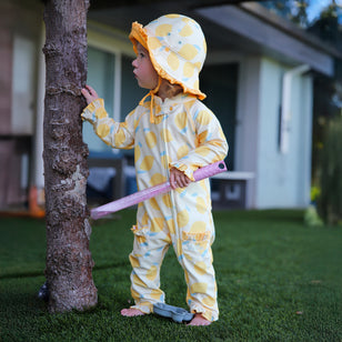 baby girl in grass by tree in baby girl one piece sun & swim suit in lemonade stand|lemonade-stand