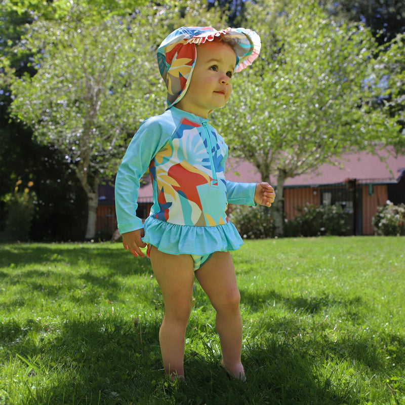 baby in grass in swim flap hat|beach-picasso